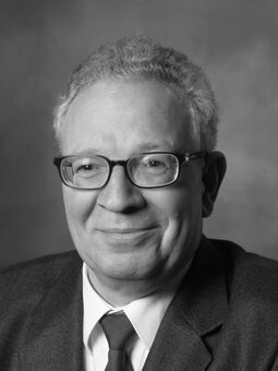 Eine Schwarz-Weiß-Aufnahme von Reinhard Bugarski. Er trägt Anzug und Krawatte, hat eine schwarze Brille und graues Haar.