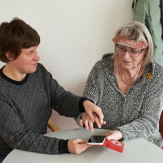 Katja Löffler, iPhone-Beraterin im BSVH, zeigt einer ratsuchenden Dame die Bedienung des Geräts