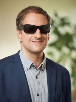 Porträtfoto des Geschäftsführers Heiko Kunert. Er trägt ein blaues Jackett über einem hellen Hemd. Sein braunes Haar ist kurzgeschnitten. Er trägt eine dunkle Sonnenbrille und lächelt in die Kamera.