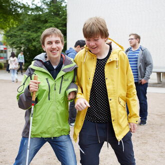 Ein blinder Schüler scherzt mit seinem sehenden Klassenkameraden auf dem Schulhof